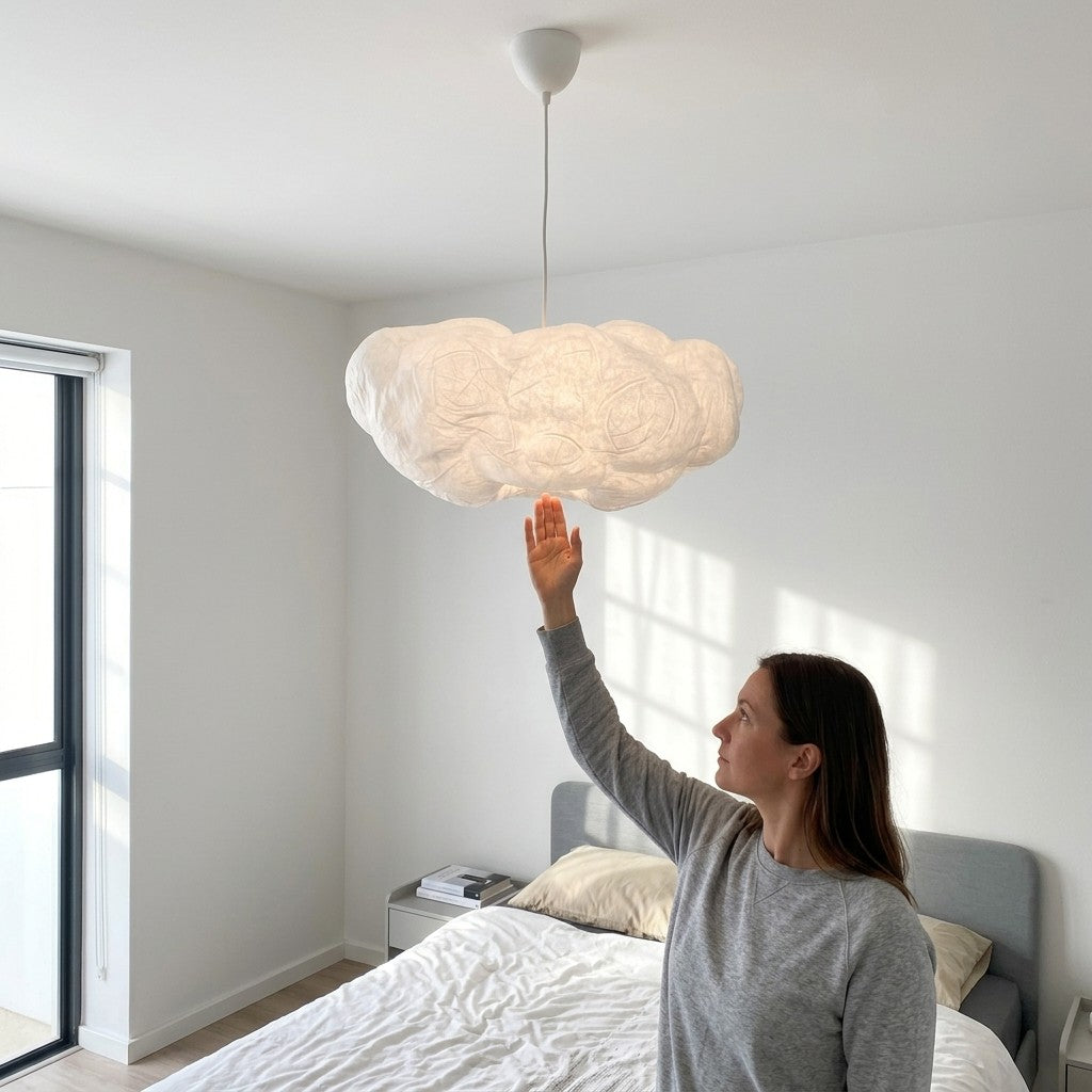 Woman reaching up to a Cloud Pendant Light showing its true size above a bed