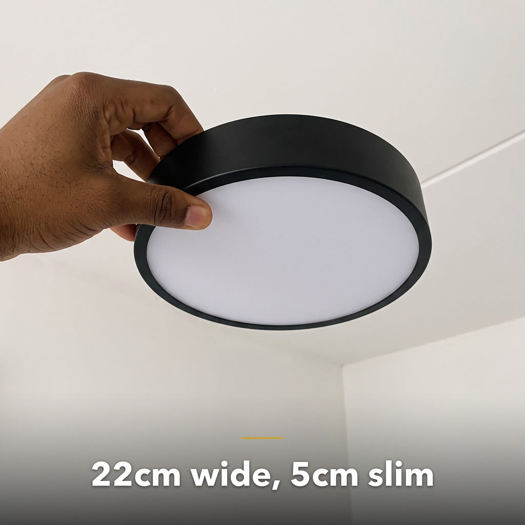 22cm black slim round LED ceiling light, held in hand to show its size