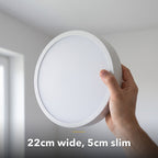 22cm white slim round LED ceiling light, held in hand to show its size