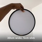 30cm black slim round LED ceiling light, held in hand to show its size