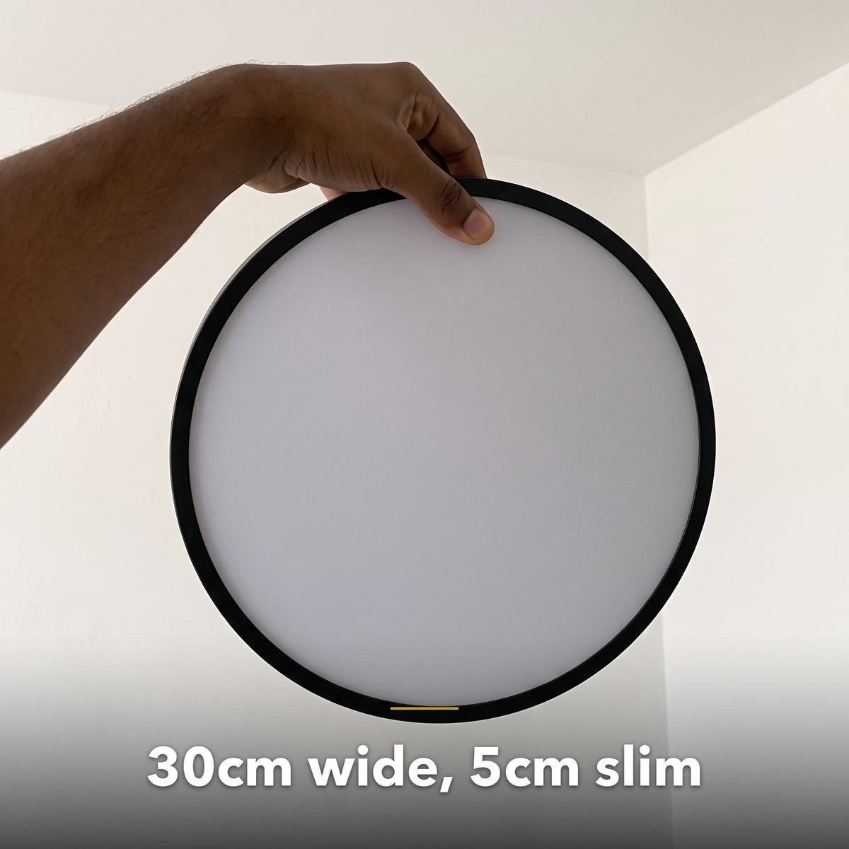 30cm black slim round LED ceiling light, held in hand to show its size