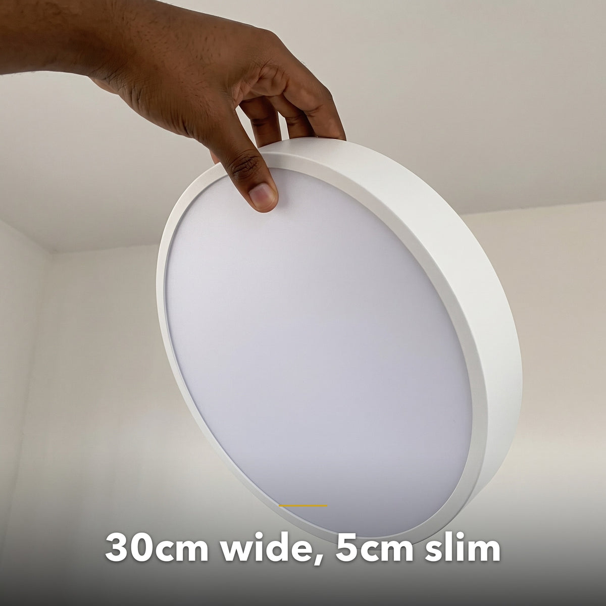 30cm white slim round LED ceiling light, held in hand to show its size