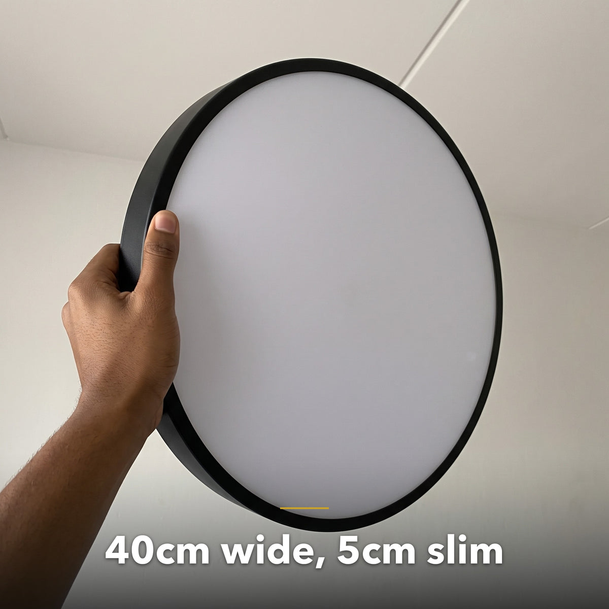 40cm black slim round LED ceiling light, held in hand to show its size